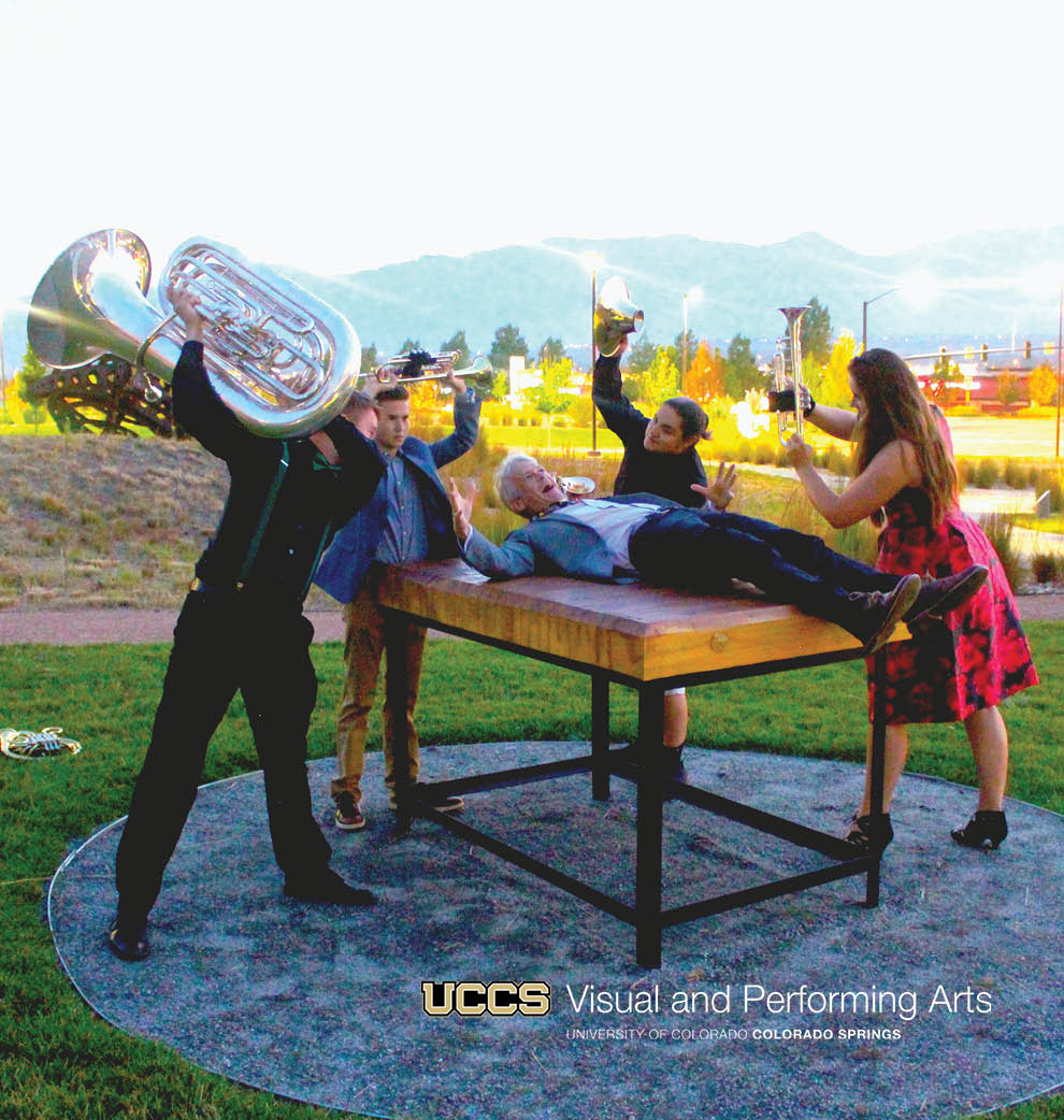 picture of quintet performers holding instruments over the instructor who's laying on a table and looks surprised